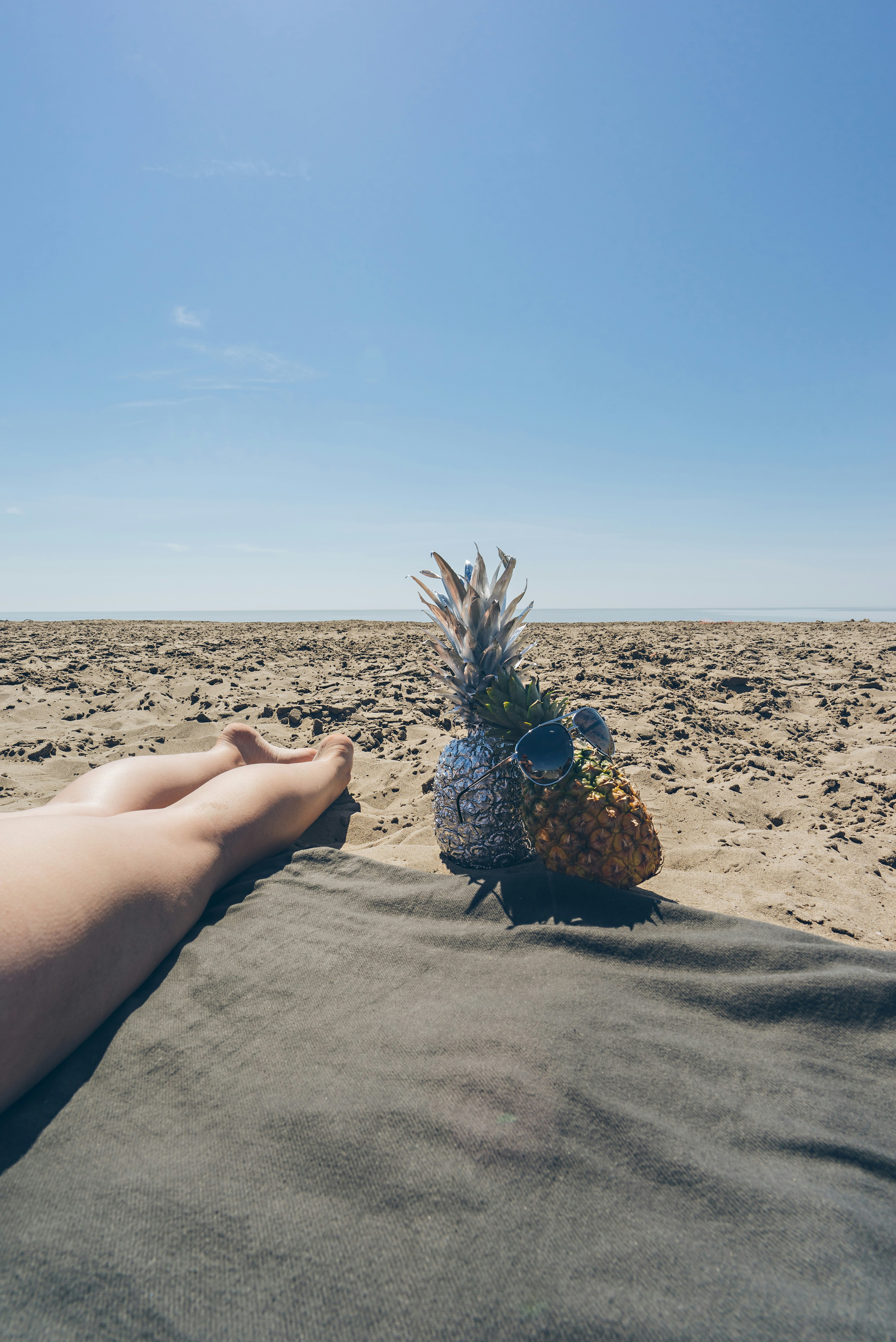 two pineapple near barefooted person on brown field